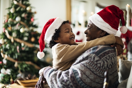 father and child hugging in front of Christmas tree